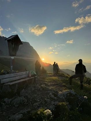 Ein malerischer Sonnenuntergang über den Bergen. Menschen genießen die Aussicht auf dem Weg.