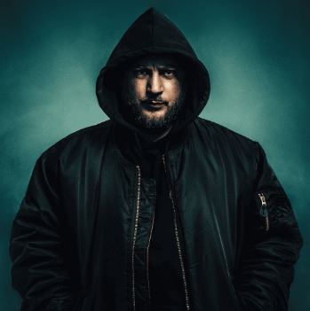 En mand ligger på jorden med et overrasket ansigtsudtryk. Han har elektroder på, og der er en redningskrans og en rød taske ved siden af ham.