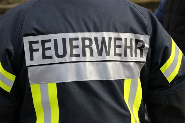 Ein Feuerwehrmann in Uniform. Auf der Jacke steht "FEUERWEHR" in großen Buchstaben.