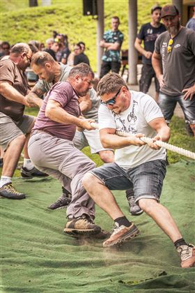 Männer ziehen in einem Tauzieh-Wettbewerb an einem Seil. Die Atmosphäre ist wettbewerbsorientiert und die Teilnehmer sind konzentriert.