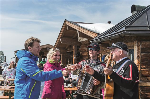 A group of friends clinks beer glasses. They are sitting at a table and enjoying their time together in a cozy setting.