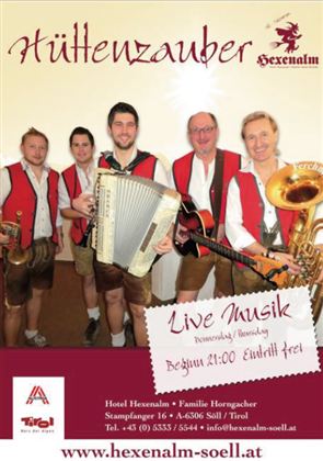 Eine Gruppe von vier Musikern in traditionellen Trachten steht auf der Bühne. Sie spielen verschiedene Instrumente und bewerben eine Live-Musikveranstaltung im Hotel Hexenalm.