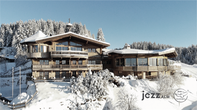 Ein wunderschönes Chalet inmitten einer schneebedeckten Landschaft. Umgeben von verschneiten Bäumen und Bergen bietet es eine gemütliche Atmosphäre.