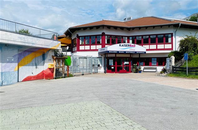 Ein modernes Gebäude mit dem Schriftzug "Kaiserbad". Es gibt bunte Wandmalereien und eine einladende Eingangstür.