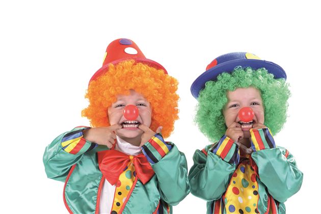 Two happy children as clowns, in colorful clothing and funny wigs. They smile and point with their hands at their red noses.