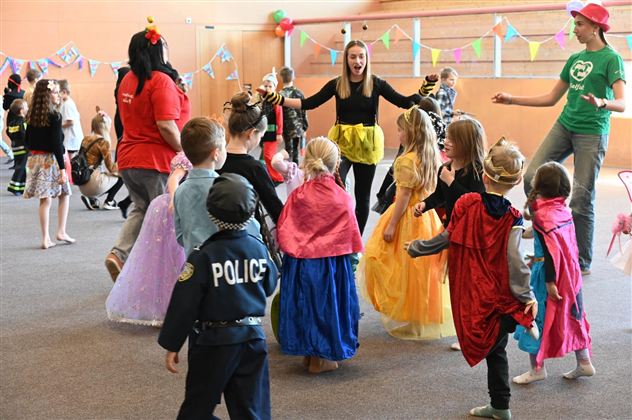 Eine lebhafte Kinderparty mit verkleideten Kindern, die Freude haben. In der Mitte tanzen und spielen sie zusammen.