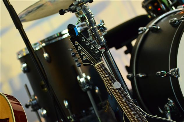 Eine Gitarre steht neben einem Schlagzeug. Die Instrumente sind bereit für die Musikaufführung.