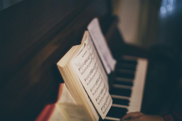 Ein Klavier mit aufgeschlagenen Notenblättern. Im Hintergrund sind die Tasten des Klaviers zu sehen.