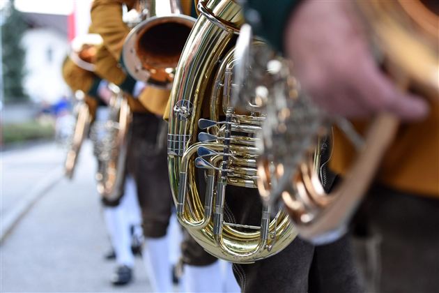 Eine Reihe von Tuben in traditioneller Kleidung. Die Musiker stehen aufgereiht in einer festlichen Atmosphäre.