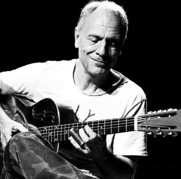 En mand ligger på jorden med et overrasket ansigtsudtryk. Han har elektroder på, og der er en redningskrans og en rød taske ved siden af ham.