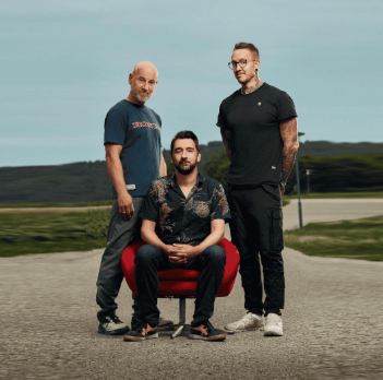 Een man ligt op de grond met een verbaasde gezichtsuitdrukking. Hij draagt elektroden en er liggen een reddingsring en een rode tas naast hem.