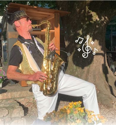 A lively music group outdoors, playing traditional instruments. In the background, guests can be seen in a relaxed atmosphere.
