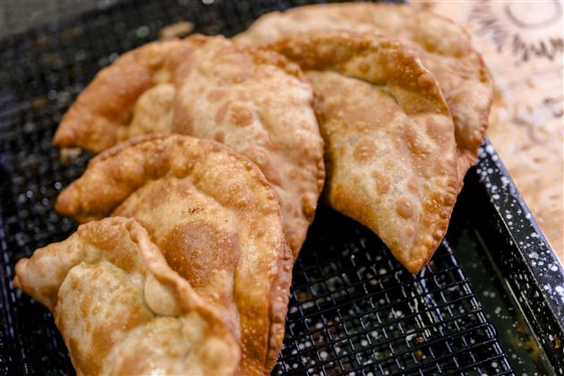 Frittierte Teigtaschen auf einem Gitter. Sie sind goldbraun und knusprig, ideal als Snack.