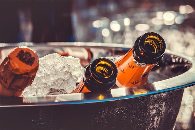 A silver bowl with ice and several bottles of champagne. The bottles are half in the ice and look festive and inviting.