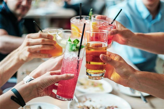 Een groep mensen toost met verschillende dranken. De glazen zijn kleurrijk en zorgen voor een vrolijke sfeer.