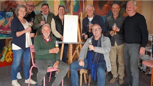A group of people stands and sits together, holding glasses in their hands. They are smiling and seem to be enjoying a celebration or an important event.