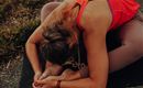 Eine Person macht eine Yoga-Übung auf einer Matte im Freien. Sie beugt sich vor und hält einen Fuß.