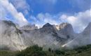 Ein beeindruckendes Bergpanorama mit felsigen Gipfeln und leichten Nebelschwaden. Der Himmel ist klar mit einigen Wolken.