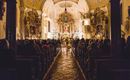 Eine besinnliche Kirche mit einer vollen Bankreihe und festlicher Beleuchtung. Im Hintergrund ist ein wunderschön dekorierter Altar zu sehen.