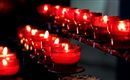 Rote Kerzen brennen in gläsernen Haltern. Sie sind auf einem Tisch angeordnet und erzeugen eine warme, einladende Atmosphäre.