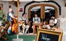 Eine Gruppe von Musikern in traditioneller Tracht spielt in einem gemütlichen Außenbereich. Die Atmosphäre ist entspannt und einladend.