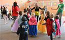 Eine lebhafte Kinderparty mit verkleideten Kindern, die Freude haben. In der Mitte tanzen und spielen sie zusammen.