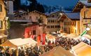 Een drukke kerstmarkt op een winteravond. Veel mensen genieten van de feestelijke sfeer en de verlichte kraampjes.