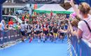 A large sporting event with many participants at the start. The atmosphere is lively and numerous spectators cheer on the runners.