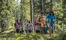 Eine Gruppe von Menschen wandert blind in einem Wald. Sie folgen einem Seil und sind von Natur umgeben.