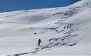 Ein Skifahrer fährt durch den frischen, unberührten Schnee. Der Himmel ist klar und blau, und die Berge bilden eine schöne Kulisse.