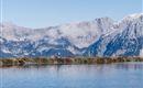 Ein stiller See umgeben von majestätischen Bergen und Wolken. Die Landschaft strahlt Ruhe und natürliche Schönheit aus.