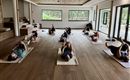 A quiet yoga room with several people lying on mats. The gentle lighting creates a relaxing atmosphere.