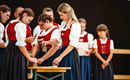 Eine Gruppe von Menschen in traditionellen Trachten steht um einen Tisch. Einige von ihnen scheinen an einer Aktivität oder Zeremonie teilzunehmen.