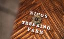 Ein Holzboden mit dem Schriftzug "Nicos Trekking Farm" und einem grünen Kranz. Die Atmosphäre ist rustikal und einladend.
