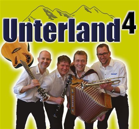 Een muziekgezelschap met vier leden houdt verschillende instrumenten in de hand. Op de achtergrond is de tekst "Unterland4" en een berglandschap te zien.