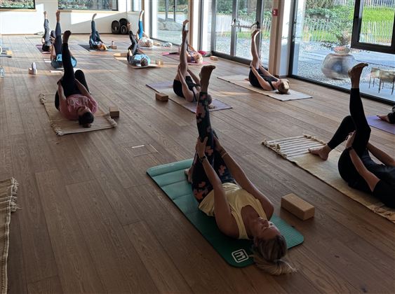 A calming yoga class in a cozy wooden room. Participants practice in a relaxed atmosphere with dim lighting.