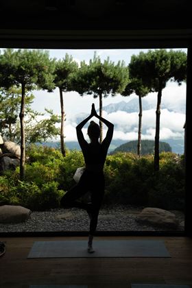 Eine Gruppe von Menschen praktiziert Yoga in einem hellen Raum. Sie sind in verschiedenen Posen und konzentrieren sich auf ihre Atmung.