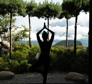 En gruppe mennesker praktiserer yoga i et lyst rum. De er i forskellige stillinger og fokuserer på deres vejrtrækning.