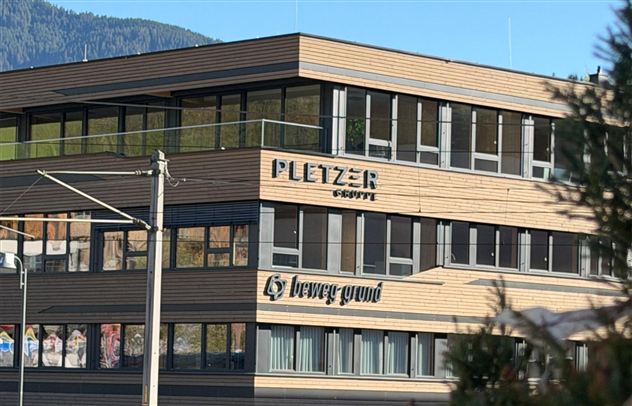 Ein modernes Gebäude mit Holzfassade. Die Unternehmensnamen "PLETZER" und "brewa grund" sind deutlich sichtbar.