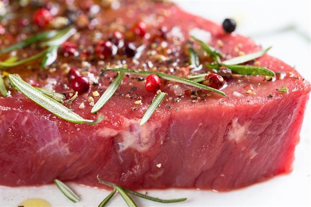 A juicy piece of meat with colorful pepper and fresh herbs. The surface is shiny and enticingly seasoned.