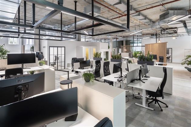 A modern office with bright workspaces and ergonomic chairs.  
Plants and large windows create a pleasant atmosphere.