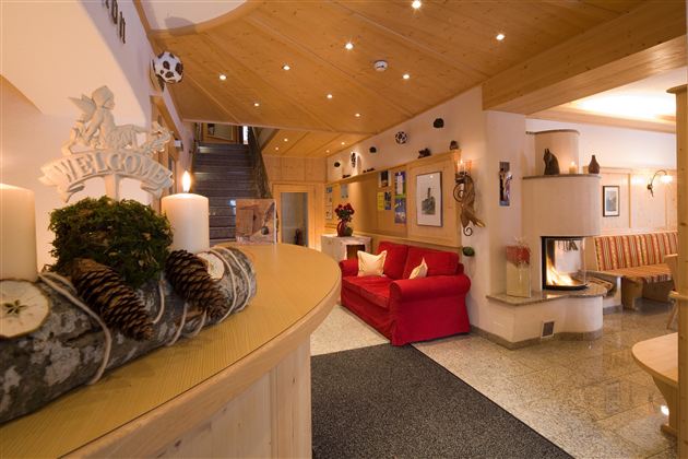 Een gezellige lounge met een rode bank en een open haard. Het ontvangstgebied is helder verlicht en hartelijk gedecoreerd.