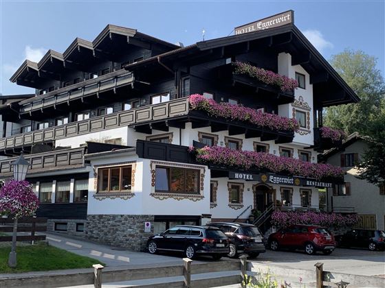 A charming hotel in traditional alpine style with blooming balcony plants. The facade is in black and white, conveying an inviting atmosphere.