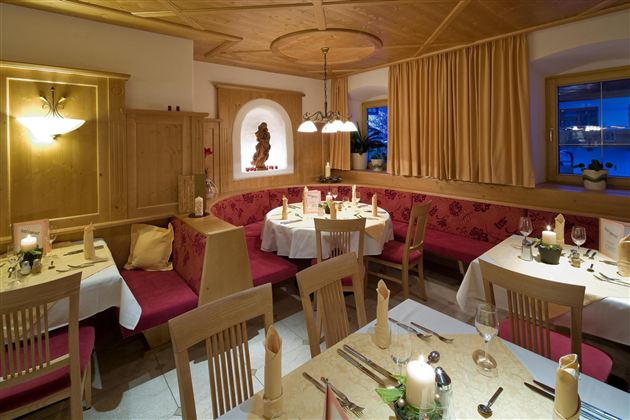 Een gezellig restaurant met houten interieur en warm licht. Tafels zijn elegant gedekt en nodigen uit om te verblijven.