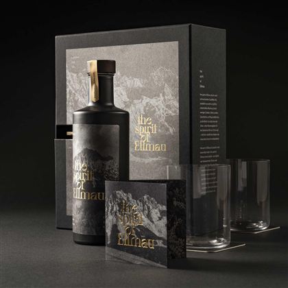 Zwarte gin-fles met bijpassende geschenkdoos, glazen en begeleidend boekje op een donkere achtergrond.