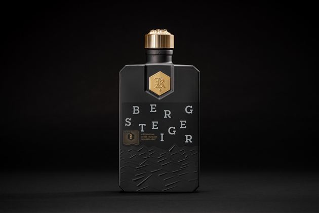 Zwarte glazen fles met gouden sluiting en de tekst Bergsteiger voor een donkere achtergrond.