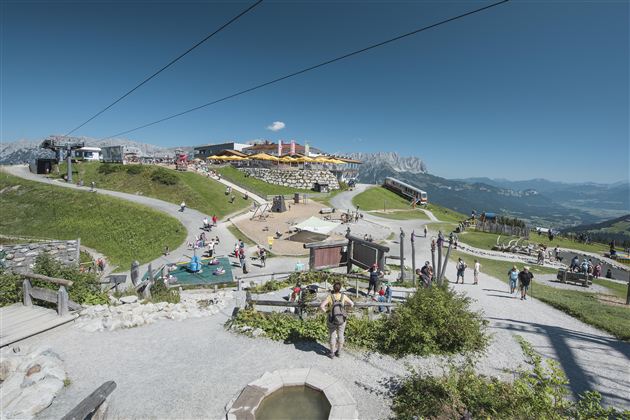 A picturesque mountain village with many visitors and clear blue sky. The surroundings are green and inviting, ideal for outdoor activities.