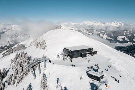 A snow-covered mountain landscape with a modern mountain station and lifts. Many people enjoy winter activities in the beautiful surroundings.