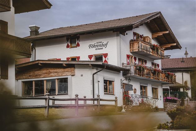 Een traditioneel gebouw met houten bekleding en een balkon. Het is in een rustige omgeving met mooie bloembakken versierd.