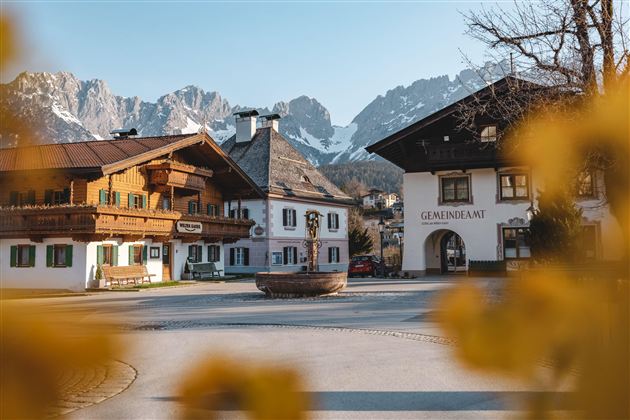 A picturesque village with traditional wooden house architectures and mountains in the background. The scenes convey a calm, alpine atmosphere.